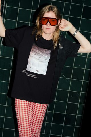 model in a t-shirt with photo from angelica blechschmidt standing in bathroom at hotel chateau royal as photographed by christian werner